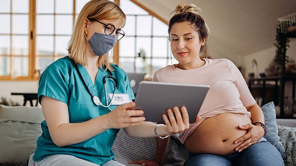 Pregnant woman looking at a tablet with a female doctor